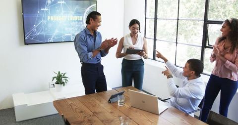 Diverse colleagues celebrating success in modern office meeting