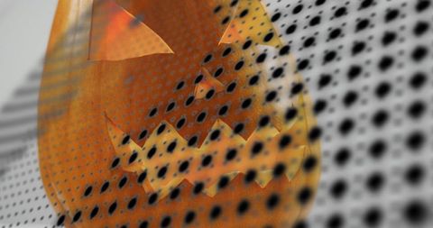 Glowing carved jack-o'-lantern peering through dotted mesh, warm studio glow