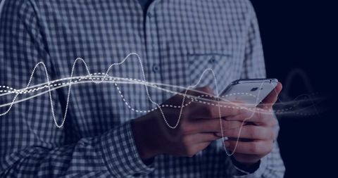 Hands holding smartphone with digital waveforms overlay, low-light business technology