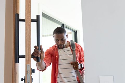 African american commuter entering modern home carrying satchel and opening front door