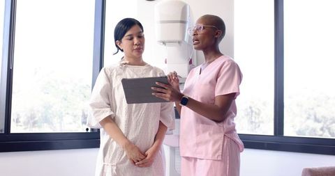 African American clinician discussing mammogram with patient in gown at clinic
