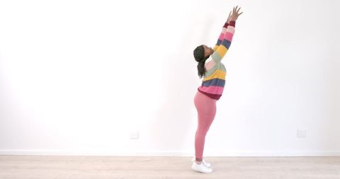 Woman in Colorful Outfit Stretching in Minimalist Space