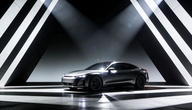 Metallic silver luxury sedan receiving spotlight on circular stage with dramatic lighting