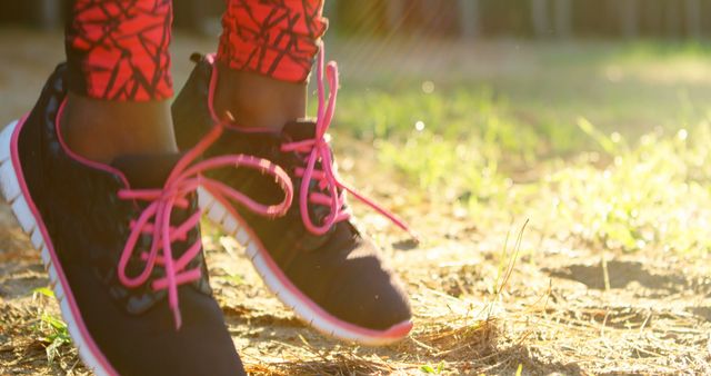 Shoes of african american sportswoman jumping in forest on sunny day. Summer, exercise, fitness, healthy lifestyle, nature.
