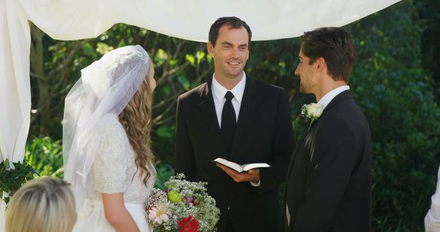 Outdoor wedding ceremony with couple and officiant under white arch - Download Free Stock Images Pikwizard.com