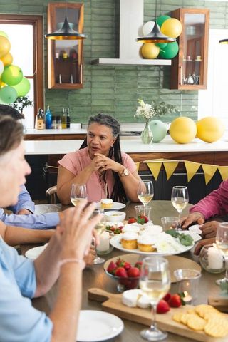 Multigenerational friends celebrating around rustic kitchen table with cupcakes and wine