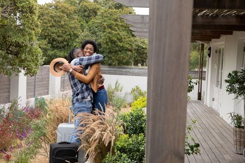Joyful Reunion: Couple Embracing at Patio with Luggage
