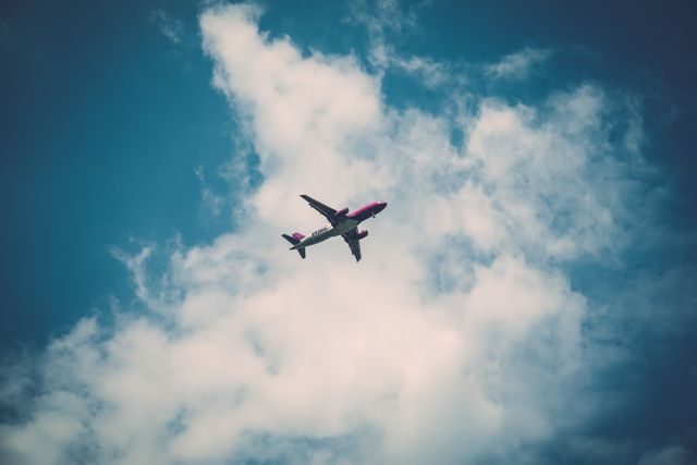 Passenger airplane flying against blue sky with scattered clouds, perfect for travel-related content, airlines advertisements, aviation articles or educational materials about transportation systems.