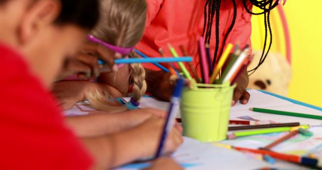 Young children immersed in drawing and coloring with colorful pencils at a classroom table. Perfect for illustrating educational materials, promoting creative activities for kids, and advertisements for children's art supplies and educational institutions.