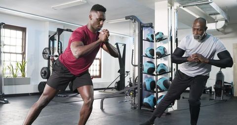 Fitness trainer guiding client in side lunges at gym