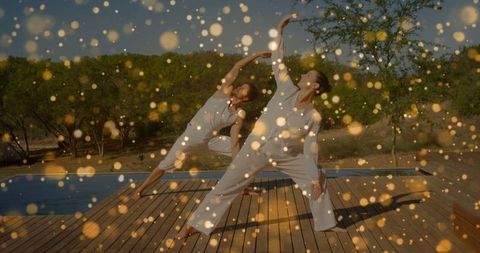 Floating lights over couple doing yoga outdoors