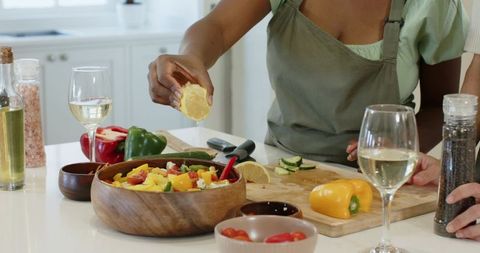 Friends preparing colorful salad in modern home kitchen
