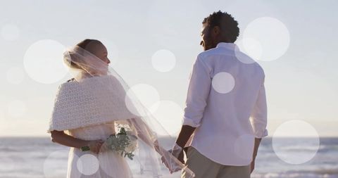 this romantic scene features an african american couple celebrating their wedding on a sunny beach. the bride holds a bouquet and gracefully wears a veil, adding an element of elegance and tradition. light spots overlay the image, creating a dreamy and whimsical ambiance. perfect for use in advertising romantic beach weddings, representing diversity in wedding photography, or illustrating articles about interpersonal relationships.