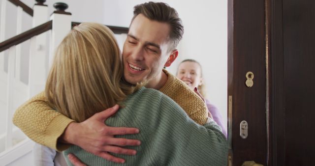 Young man warmly hugging two women at a home entrance, signifying an emotional and joyful reunion. Ideal for depicting family bonds, homecomings, and greeting moments. Perfect for use in advertisements, editorial features, or social media posts celebrating family reunions, warmth, and connections.
