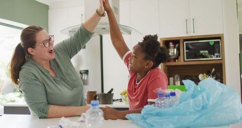 Mother and Daughter Joyfully Sorting Waste in Kitchen