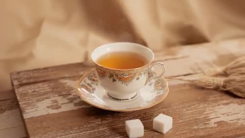 Dolly-in on steaming porcelain teacup and sugar cubes over rustic wooden table