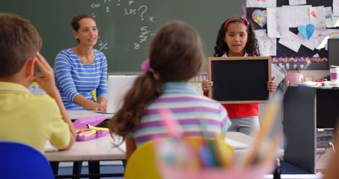 Engaged Schoolgirl Presenting Slate to Class - Download Free Stock Images Pikwizard.com