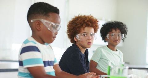 African american boys conducting science experiments in school lab wearing safety goggles