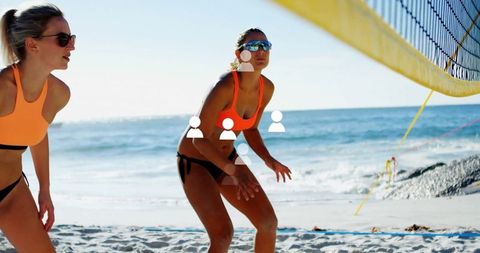 Women Engaging in Vibrant Beach Volleyball Game Under Clear Sky
