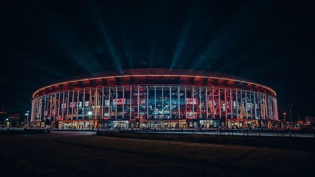 Illuminated modern stadium with glass facade and vertical columns