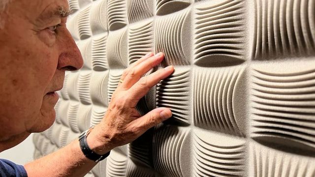 Senior man touching textured modular wall panel closeup tactile exploration