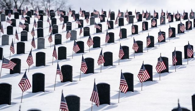 American flags marking snow-covered military graves on serene hillside for remembrance