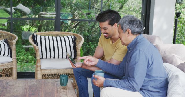 Young Man and Senior Man Enjoying Tablet and Coffee in Living Room - Download Free Stock Images Pikwizard.com