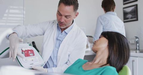 Dentist explaining dental model to patient in modern clinic during consultation
