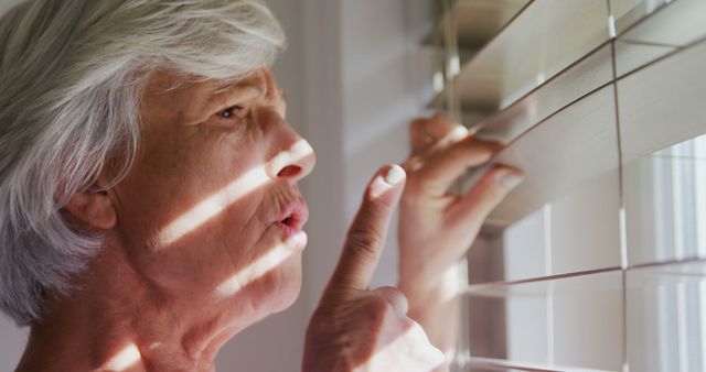 Senior Woman Peeking Through Window Blinds in Suspense - Download Free Stock Images Pikwizard.com