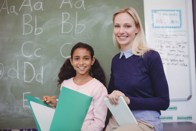 Portrait of smiling teacher and schoolgirl in classroom - Download Free Stock Photos Pikwizard.com