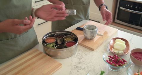 African american couple grinding spices together in modern kitchen with mortar and spice box
