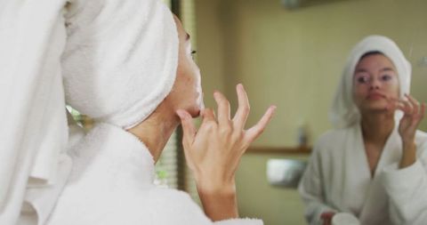 Woman Applying Skincare in Bathroom Mirror Reflection