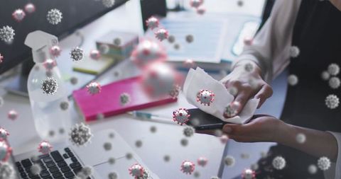 Sanitizing smartphone in office during pandemic with virus conceptual overlay