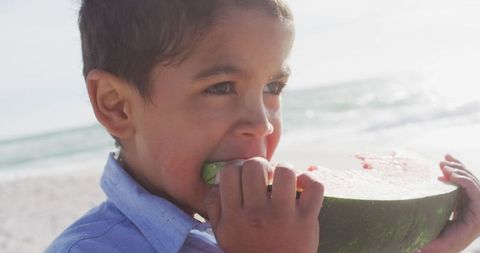Young Boy Enjoying Watermelon at Sunny Beach