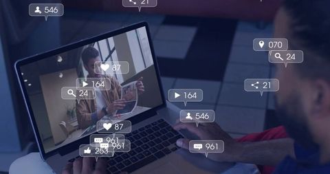Bearded man watching live stream on laptop with floating social media engagement icons
