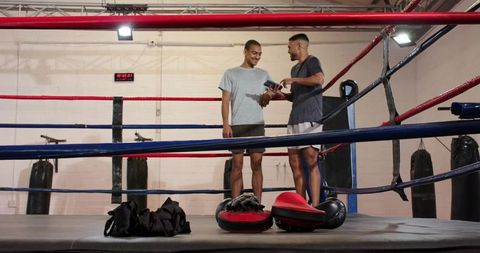 Boxing trainer checking device with boxer in ring showing focus mitts during training