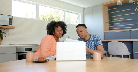 African American Couple Engaging in Conversation at Home with Laptop