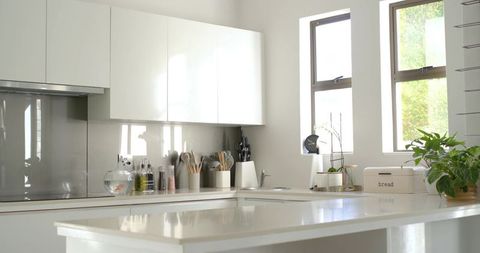 Sunlit Minimalist White Kitchen Island with Glossy Countertop, Organized Utensils, Orchid