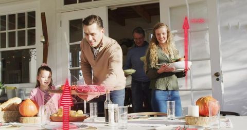 Multigenerational family gathering at sunlit dining table with pumpkin fall decor