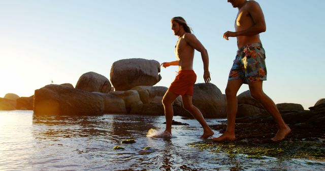 Two Men Walking Along Rocky Beach at Sunset - Download Free Stock Images Pikwizard.com