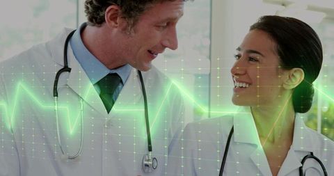 Doctors Consulting and Smiling with Digital ECG Overlay Representing Patient Care