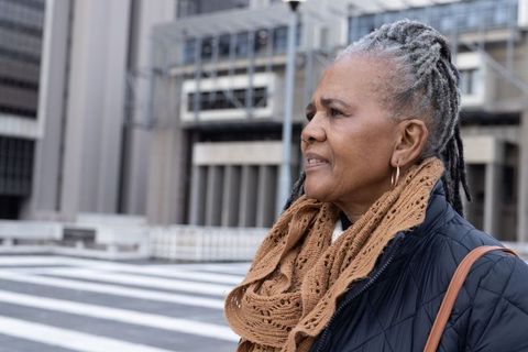 Senior african american woman waiting at urban crosswalk wearing scarf and coat