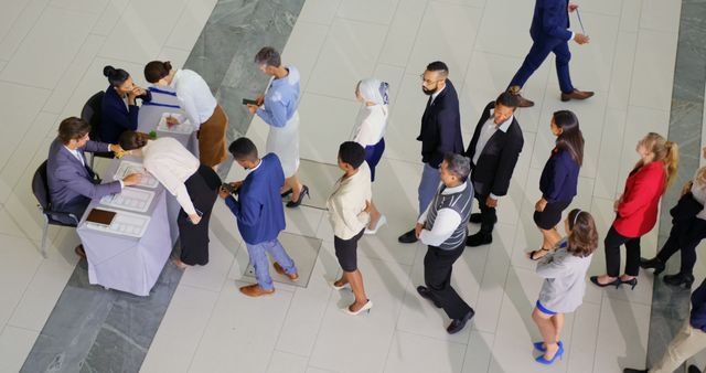 People standing in line waiting at job fair registration desk in a professional setting. Suitable for themes related to job fairs, professional events, networking, business, career opportunities, and human resources.