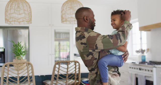 Depicts emotional reunion of military father and child in modern kitchen. Perfect for topics on family bonding, military families, homecoming stories, and promoting parent-child relationships. Useful for websites, advertisements, and emotional storytelling in blogs and articles.