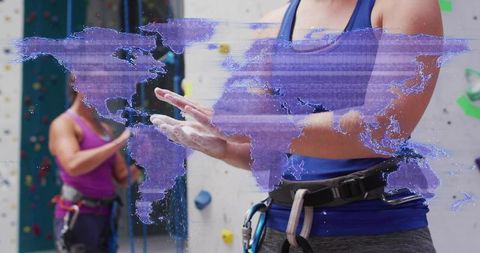 Female climber applying chalk in gym harness with digital world map overlay for global training