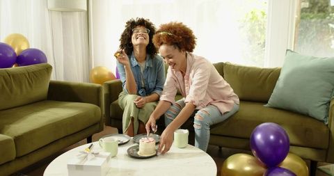 African American friends celebrating with cake and balloons in cozy living room