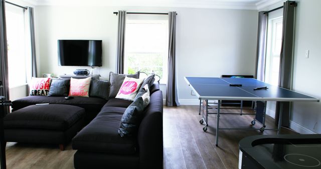 Modern living room with sectional sofa and table tennis setup - Download Free Stock Images Pikwizard.com