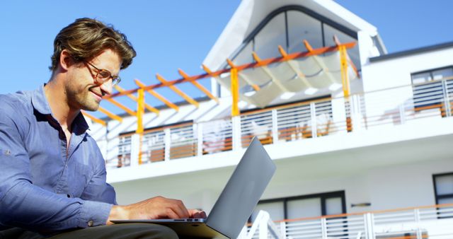 Remote Worker Typing on Laptop with Modern Home in Background - Download Free Stock Images Pikwizard.com