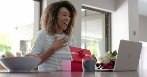 Joyful Woman Opening Gift During Virtual Celebration at Home