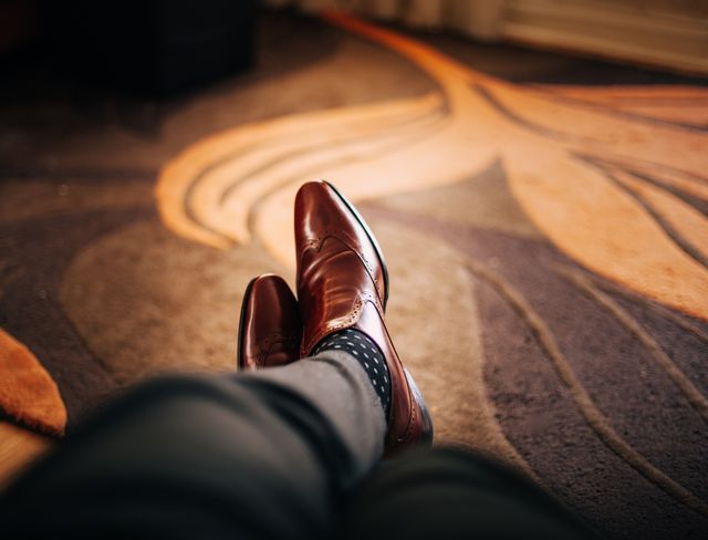 Man wearing stylish leather shoes and polka-dot socks, lying down inside, showcasing comfort and casual style. Useful for fashion blogs, lifestyle content, product promotion, or relaxation themes.